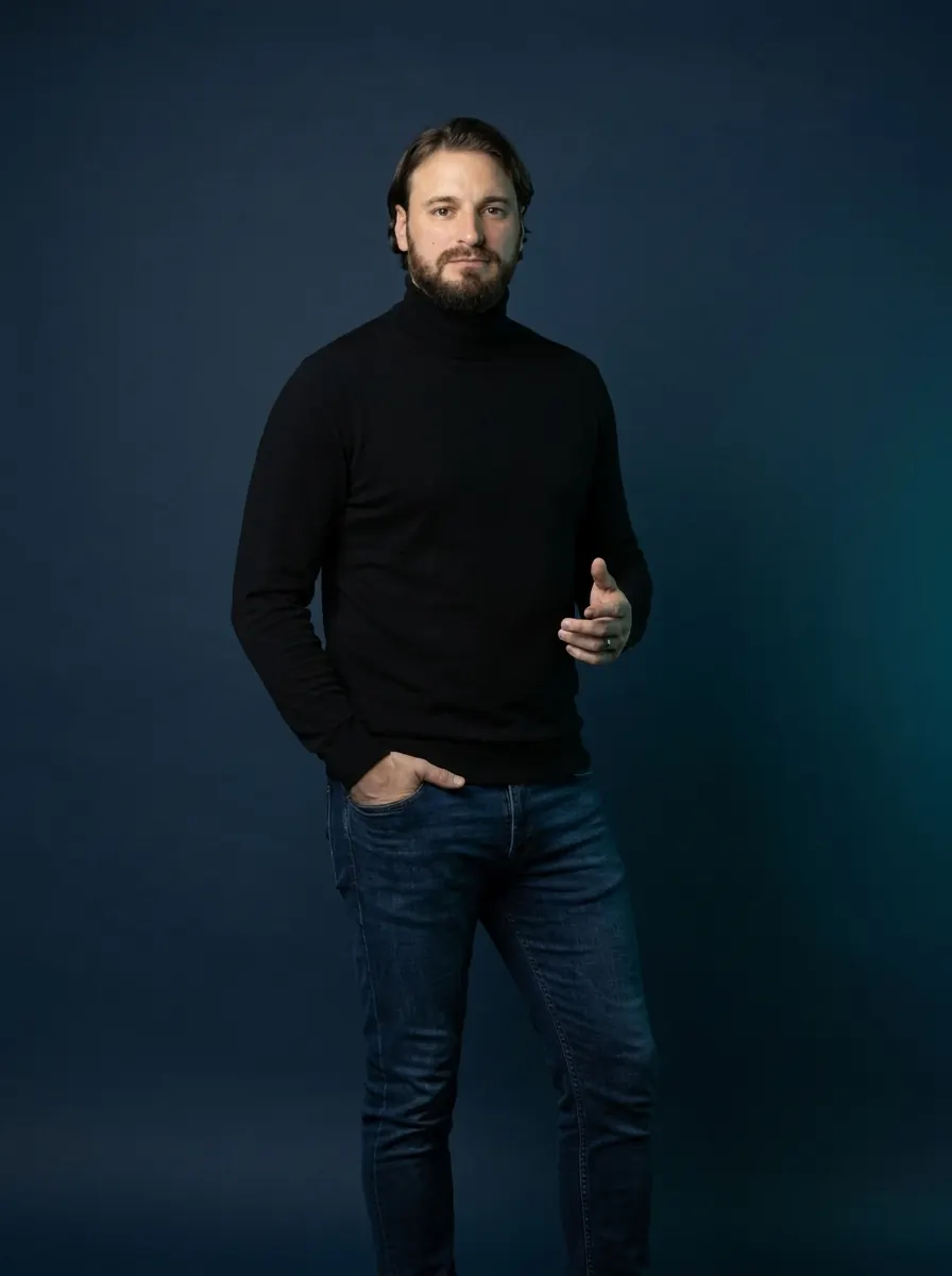 Alessio Vinassa in a black turtleneck against a deep blue studio backdrop