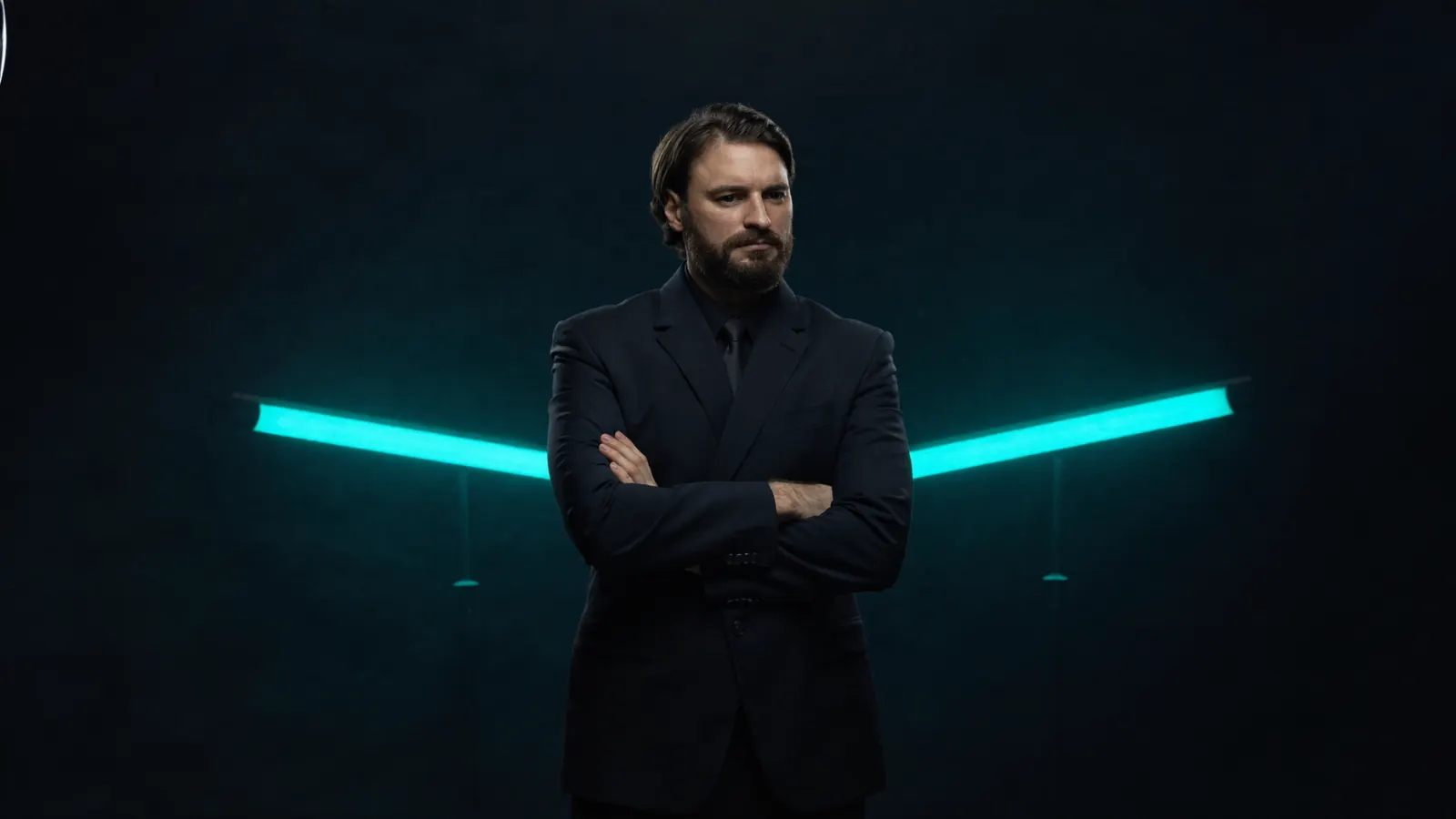 Alessio Vinassa in a tailored dark suit against a moody teal-lit background